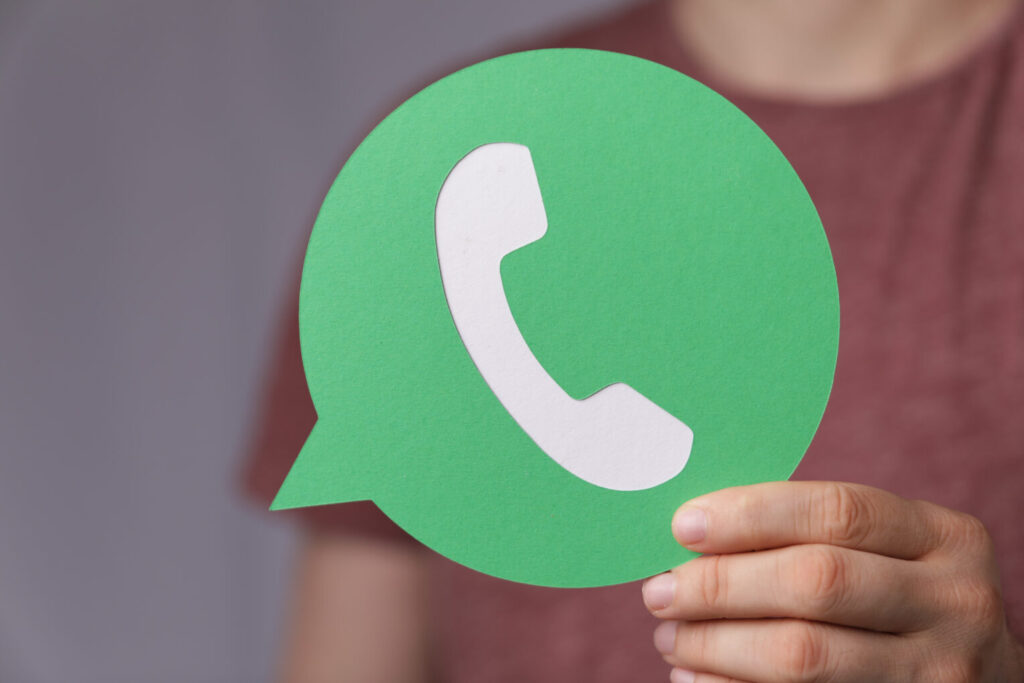 Osoba trzyma duze logo papierowe whatsapp