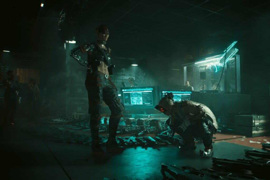 screeen z gry cyberpunk 2077. WIdac dwie postacie - kobieta stoi, mezczyzna kuca obok
