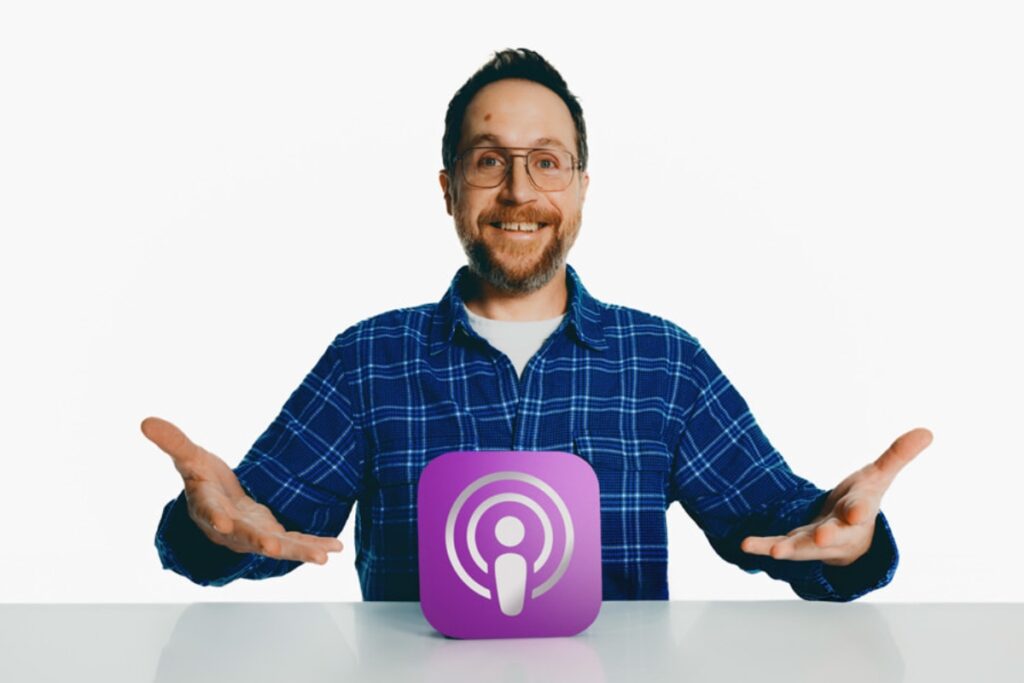 Człowiek siedzi przy stole i wskazuje na logo apple podcasts